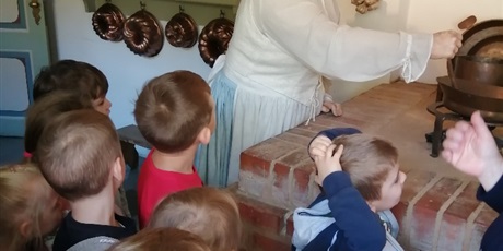 Powiększ grafikę: Dzieci z grupy Pszczółki obok wystawy pieca i kucharki w Domu Uphagena.