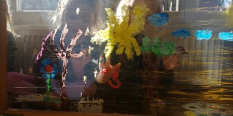 Powiększ grafikę: Dwoje dzieci z grupy Pszczółki malują farbami na folii przezroczystej.