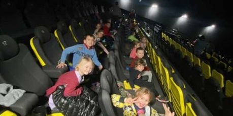 Powiększ grafikę: Usmiechnięte dzieci z grupy Słoneczek siedzą na fotelach w kinie Helios.