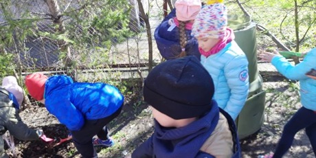 Powiększ grafikę: Dzieci z grupy Słoneczek w ogrodzie przedszkolnym wsypują ziemię do kompostownika.