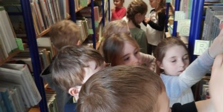 Powiększ grafikę: Dzieci z grupy Słoneczek w Szkole Nr 50 w bibliotece szkolnej oglądają książki.