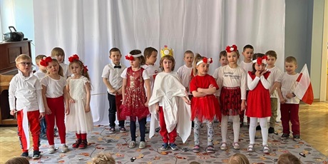 Powiększ grafikę: Dzieci z grupy Motylków ubrane na biało czerwono przedstawiają patriotyczny występ na sali gimnastycznej.