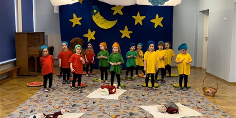 Powiększ grafikę: Dzieci z grupy Biedronek w kolorowych strojach wystepują w przedstawieniu. W tle dekoracja nocy z księżycem i gwiazdami.