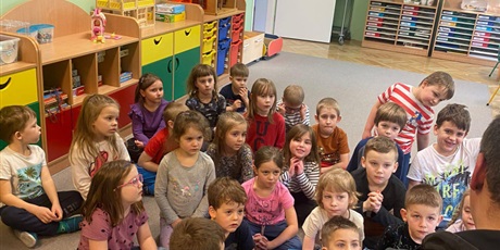 Powiększ grafikę: Dzieci z grupy Słoneczka i Motylki wysłuchują książki czytanej przez tatę w ramach akcji "Czytanie na dywanie".